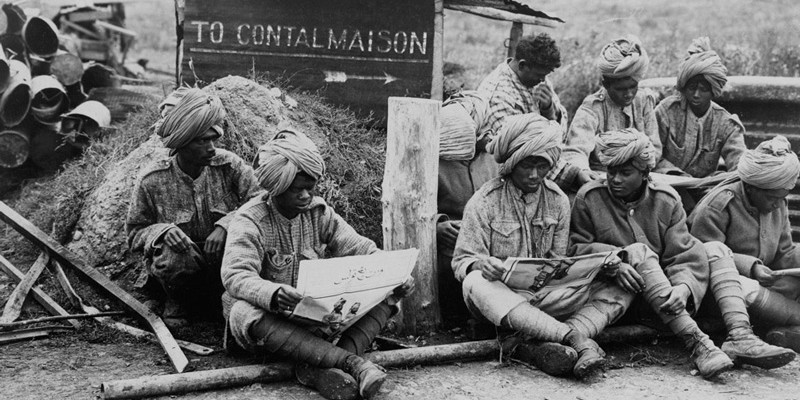 Members of an Indian Labour Battalion reading papers during a work break, c1917