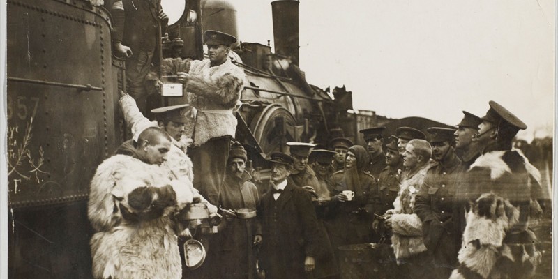 British Territorial soldiers taking refreshment during a halt. The driver supplies the hot water. Some of the men are dressed in woolly coats.