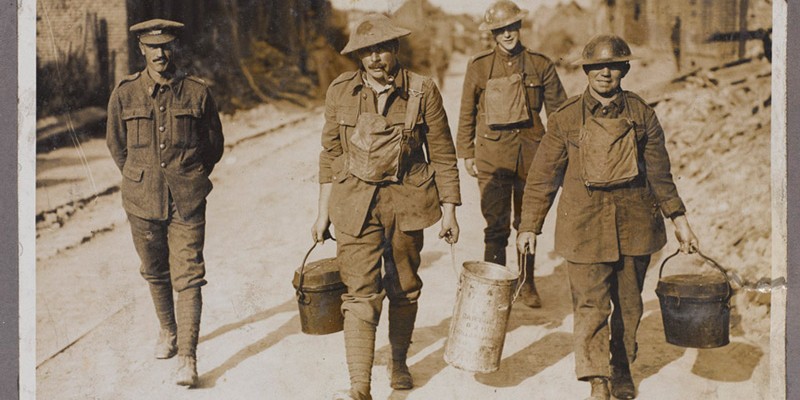 Canadian cooks with their gas masks at the alert taking tea up to the men in a village near the line, c1917
