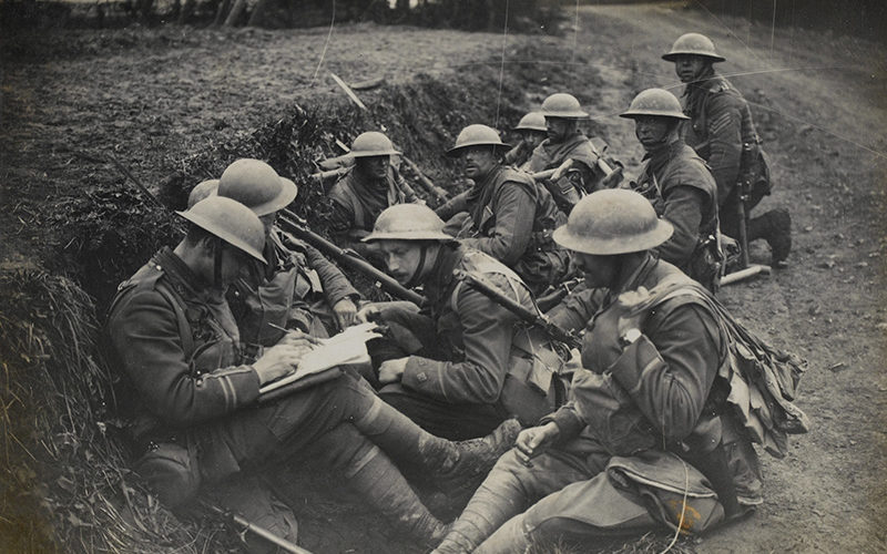 Soldiers from The Duke of Cambridge's Own (Middlesex Regiment) rest in a ditch as their officers consult a map, April 1918